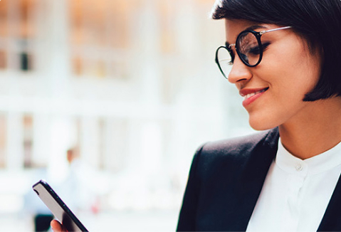 Woman looking at a phone with a smile on her face.